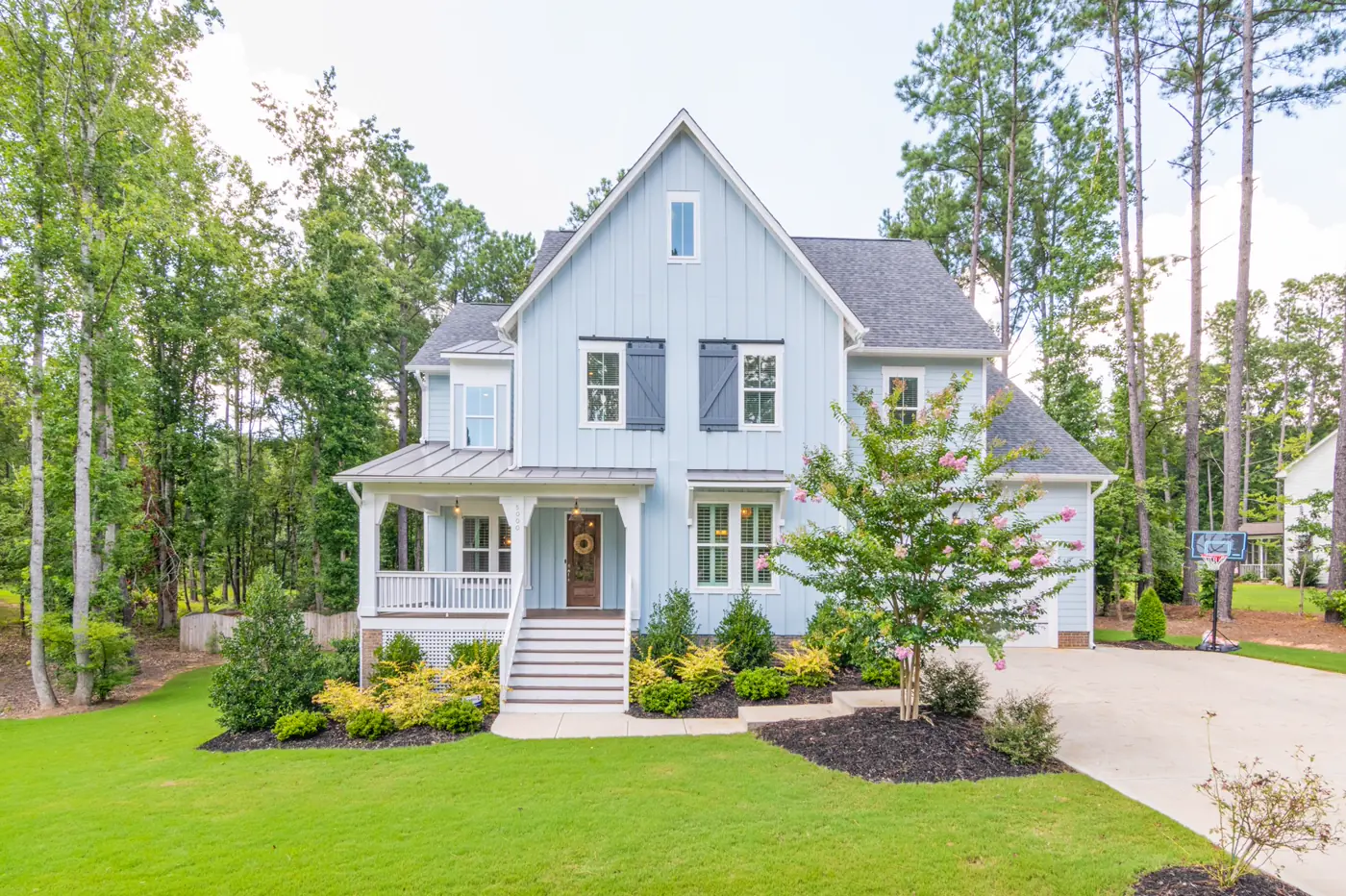 A two-story single-family home with a shingle roof and mature trees